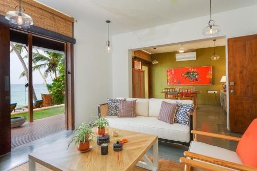 a living room with a white couch and a table at Bay Villas Balapitiya in Balapitiya