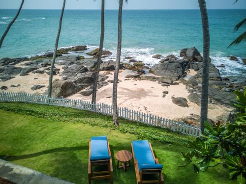 two chairs sitting on the grass near the beach at Bay Villas Balapitiya in Balapitiya