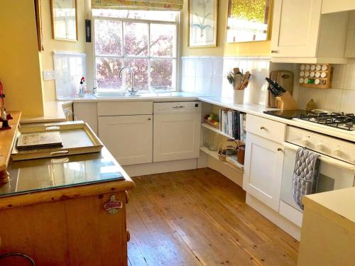 a kitchen with white cabinets and a sink and a window at Lauras Townhouse Apartments The Circus Maisonette in Bath