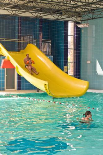 two people sitting on a yellow slide in a swimming pool at Floreal Nieuwpoort in Nieuwpoort