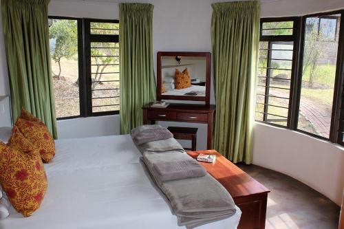 1 dormitorio con cama con espejo y mesa en Sungubala Eco Camp, en Bergville