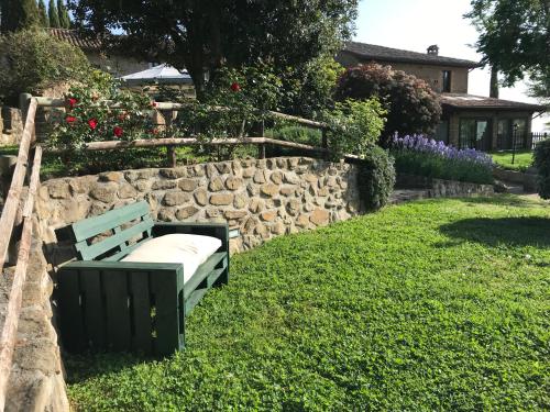 a bench sitting in the grass next to a stone wall at Le Terre Di Isa in Magione