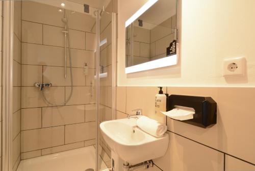 a white bathroom with a sink and a shower at The Suites City Lofts at the Park in Hamburg