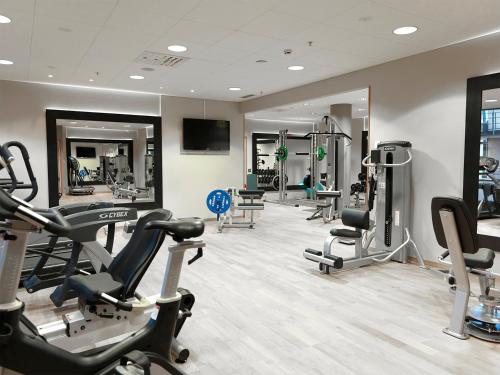 a gym with several treadmills and elliptical machines at Hotel Skansen Båstad in Båstad