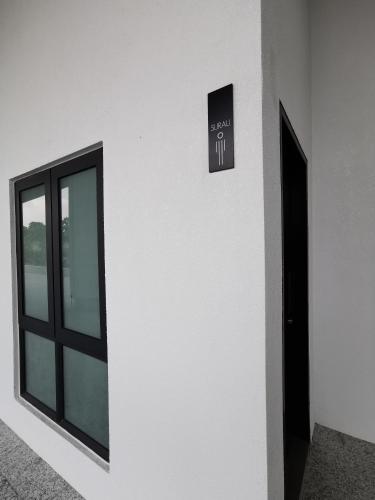 a white wall with a window and a sign on it at Almas Suites Studio Seaview Netflix By STAY in Nusajaya