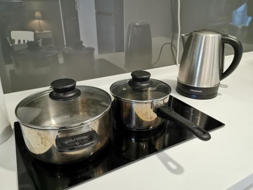 two pots sitting on top of a stove with a kettle at Almas Suites Studio Seaview Netflix By STAY in Nusajaya