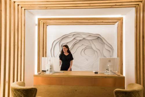 a woman standing behind a desk with two computers at Omnia Mykonos Boutique Hotel & Suites in Ornos