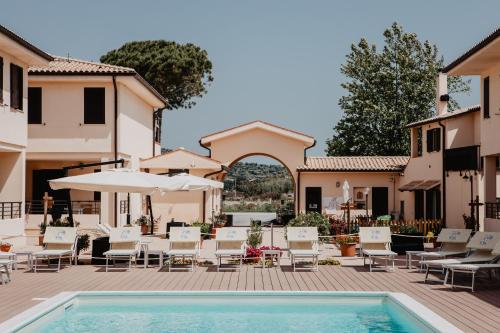 a courtyard with a pool and chairs and an umbrella at Residence Talamone Il Poderino in Talamone