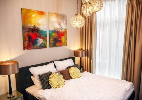 een slaapkamer met een bed met kussens en schilderijen bij Comfort and Style in City Center with Ensuite Bathroom on Schaafenstraße in Keulen