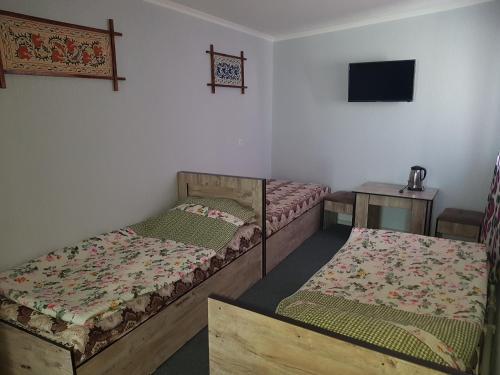 a room with two beds and a tv on the wall at Guest house IBROHIM حلال in Bukhara