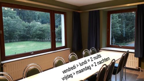 a conference room with a table and chairs and two windows at Le Moulin Lemaire in Houffalize