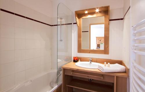 a bathroom with a sink and a shower and a mirror at Résidence Odalys Rochebrune in Orcières