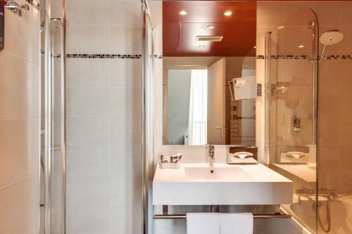 uma casa de banho com um lavatório e um chuveiro em Mercure Paris Bastille Marais em Paris