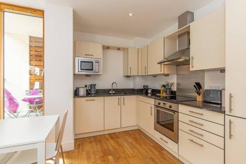 a kitchen with white cabinets and a white table at Oxfordshire Living - The Lewis Apartment - Oxford in Oxford