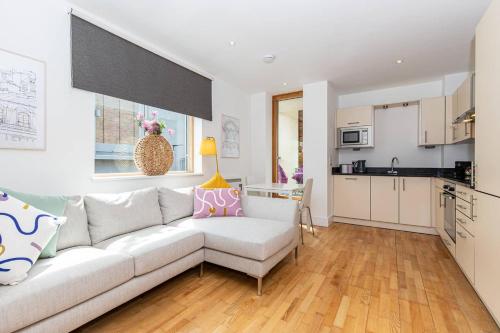 a living room with a white couch and a kitchen at Oxfordshire Living - The Lewis Apartment - Oxford in Oxford
