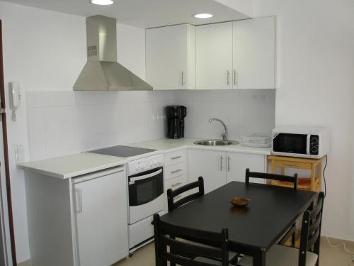 a kitchen with white cabinets and a black table with chairs at Roses Holiday Center 2408 in Roses