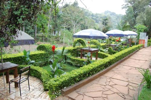 a garden with tables and chairs and umbrellas at Kakakuona Resort in Lushoto