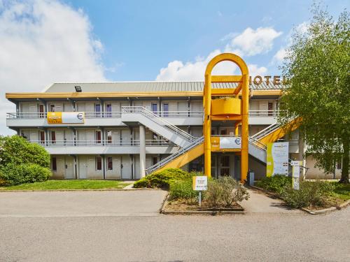 an office building with a yellow spiral staircase in front of it at Première Classe Melun Senart in Vert-Saint-Denis