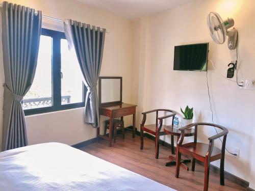 - une chambre avec un lit, un bureau et une télévision dans l'établissement Le Grey Dalat Hotel, à Đà Lạt