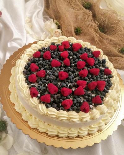 a cake with blueberries and raspberries on a table at Relais Santo Stefano in Sandigliano