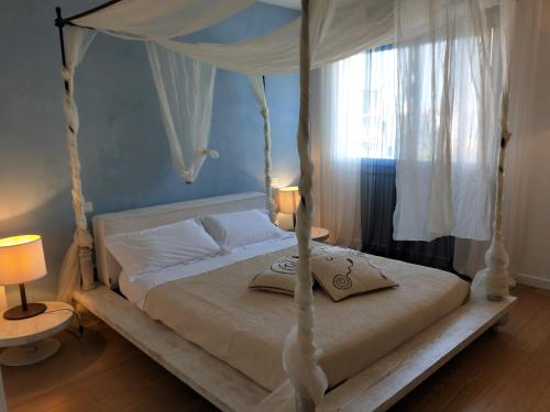 1 dormitorio con 1 cama blanca con dosel en Heron apartments, en Lido di Jesolo