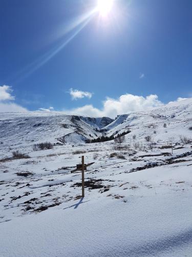 a cross in a snowy field with a snow covered hill at Guesthouse Gamli Bær in Húsafell