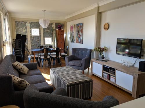 a living room with a couch and a tv and a table at Magenta Cottage in Tumbarumba