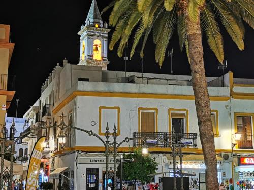 a clock tower on top of a building with a palm tree at Villa Yandre Garden House - Ayamonte in Ayamonte