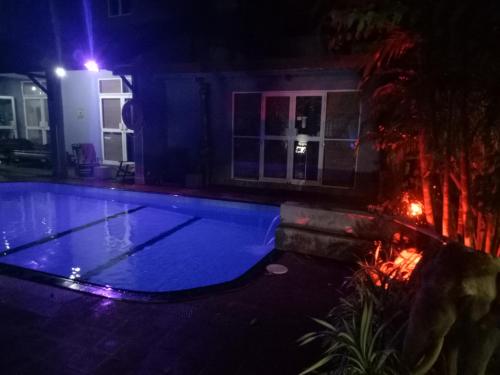 a large blue swimming pool in a house at night at Palms Villa in Negombo