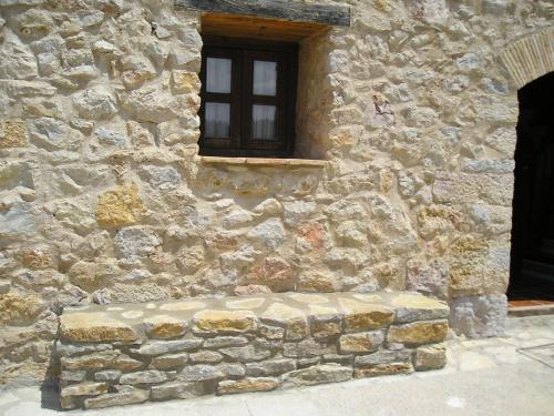 a stone building with a window and a stone bench at Casa La Mestra in Herbeset