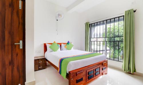 a bedroom with a bed and a large window at Treebo New Redfern, Madikeri in Madikeri