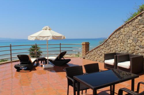 a patio with chairs and tables and an umbrella at Pictures Suites in Agios Stefanos