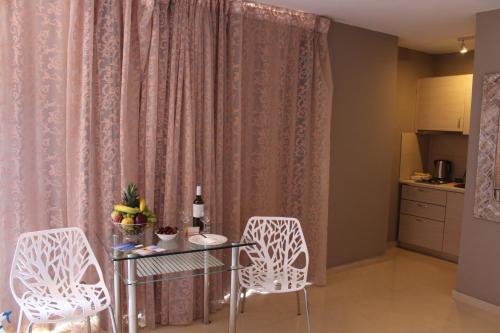 a dining room with a glass table and two chairs at Pictures Suites in Agios Stefanos