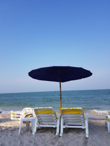 two chairs and an umbrella on the beach at Plaza Huahin in Hua Hin