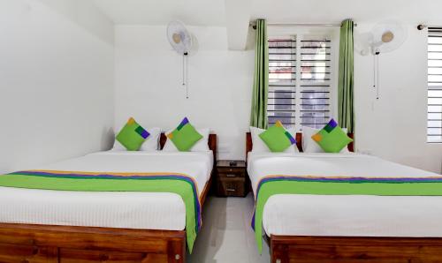 two beds in a room with white walls at Treebo New Redfern, Madikeri in Madikeri
