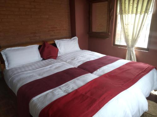 a large bed with a red and white striped blanket at Golden Gate Guest House in Bhaktapur