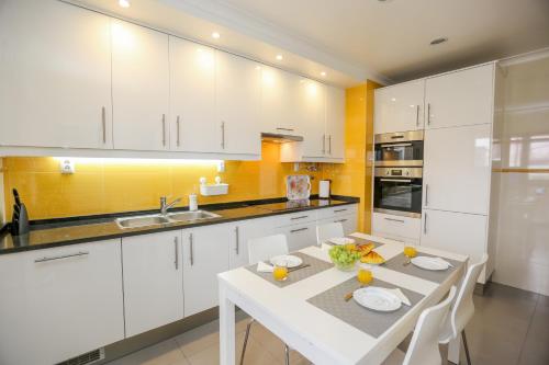 a kitchen with white cabinets and a white table at Like-home-T4-Bright Benfica Apt-Terrace in Lisbon