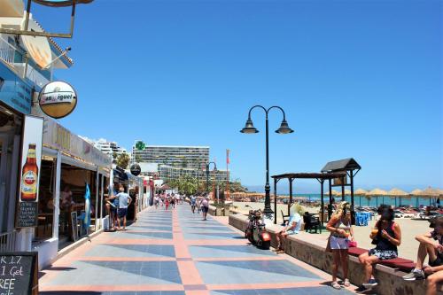 people walking on a sidewalk next to the beach at Hotel Cabello in Torremolinos