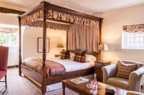 a bedroom with a four poster bed and a chair at Old Swan in Minster Lovell