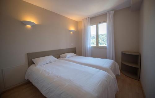 a bedroom with a white bed and a window at Appart Hotel Lou Castelet in Carros