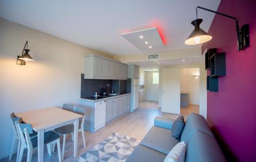 a living room with a couch and a table and a kitchen at Appart Hotel Lou Castelet in Carros