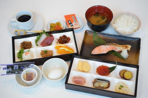 una mesa con tres bandejas de diferentes tipos de alimentos en Queens Hotel Chitose, en Chitose