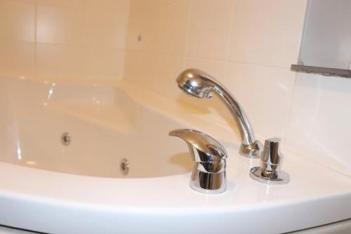 a bathroom sink with a white tub and a silver faucet at Struer Town Apartment in Struer