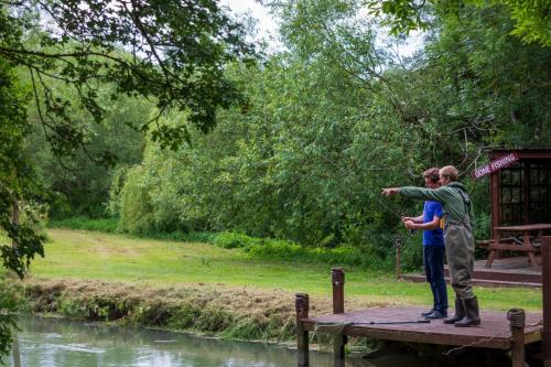 two people are standing on a wooden pier looking at a river at Old Swan & Minster Mill in Minster Lovell