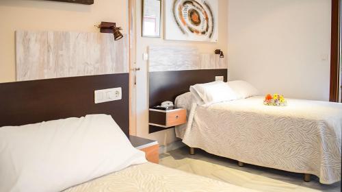 a bedroom with two beds and a mirror at Hotel Albero in Granada