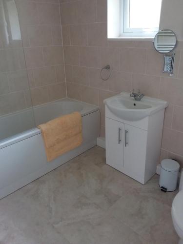 uma casa de banho com uma banheira, um lavatório e um WC. em Alderman Peel High School Bungalow em Wells next the Sea