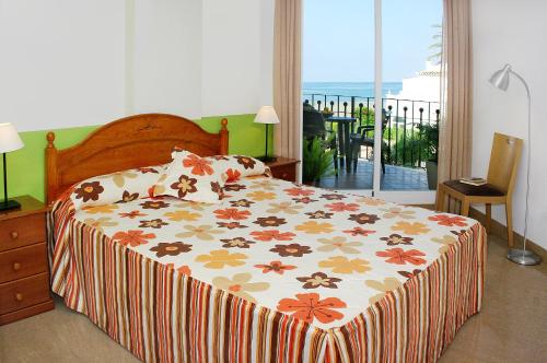 a bedroom with a bed and a balcony with a view at Apartamentos Euromar Playa in Torrox Costa