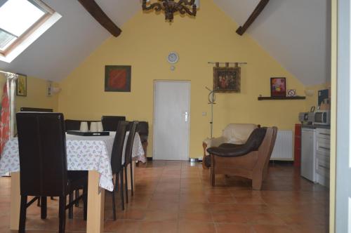 a dining room with a table and chairs and a kitchen at Le Gîte de la Gentilhommière du Château de Ragnies. in Lyrée