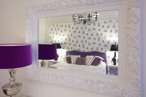 a mirror in a bedroom with a bed and two lamps at Hotel Apia in Vilnius