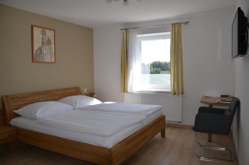 a bedroom with a bed and a window and a chair at Gasthof Haselberger in Marbach an der Donau